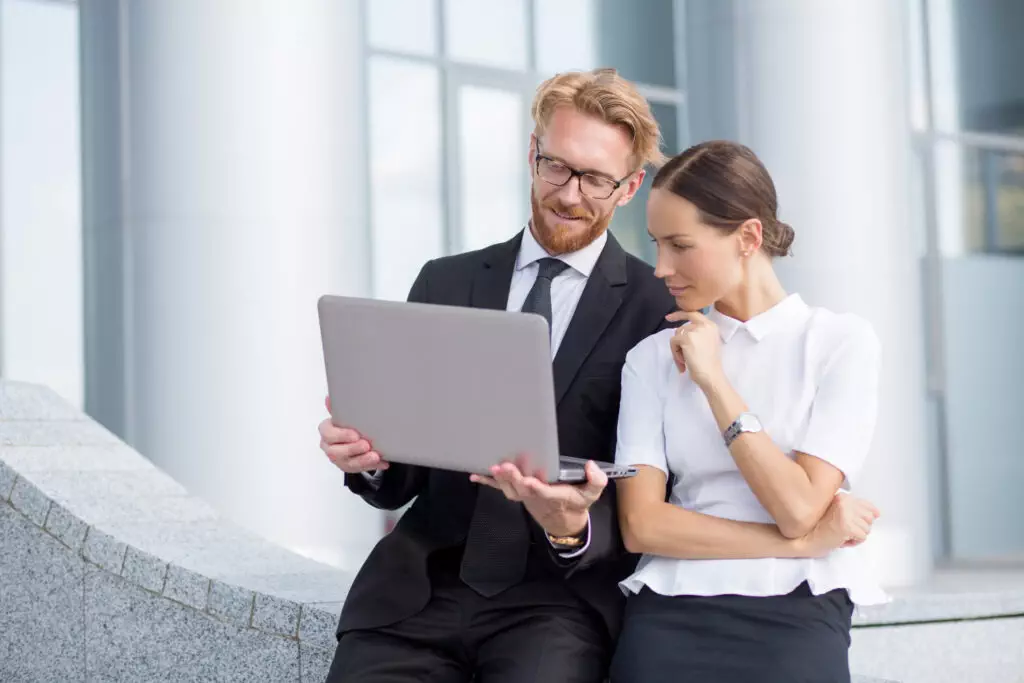 a man and woman looking at a laptop