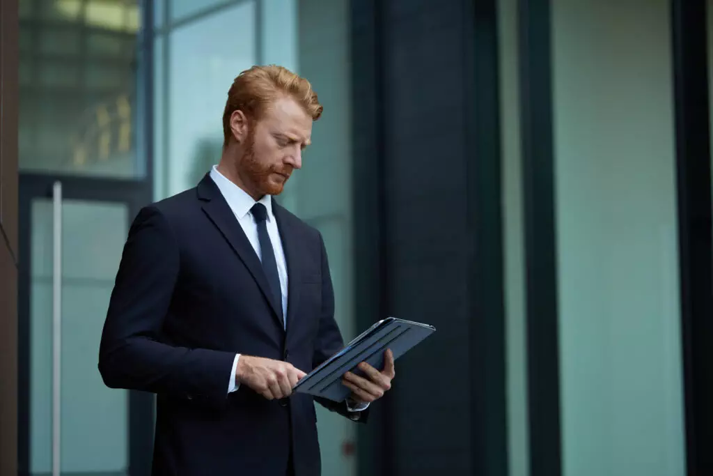 a man in a suit and tie looking at a tablet