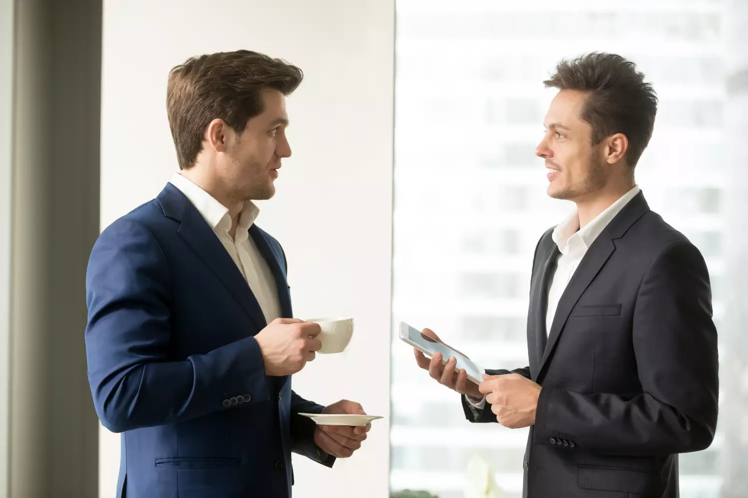 two men in suits holding cups and a phone