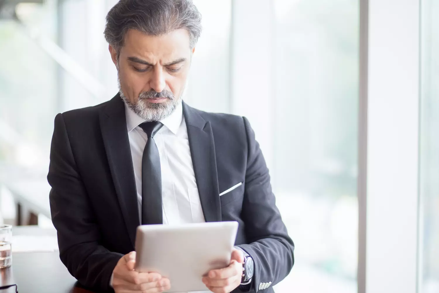 a man in a suit and tie looking at a tablet