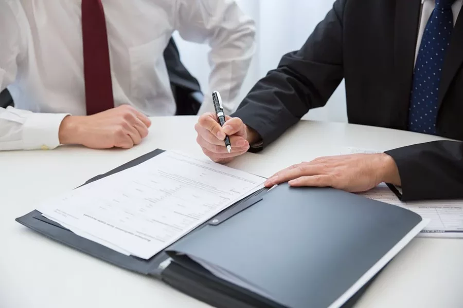 Two individuals review a form FS01 AFSL application at a desk, one holding a pen, ready to sign.