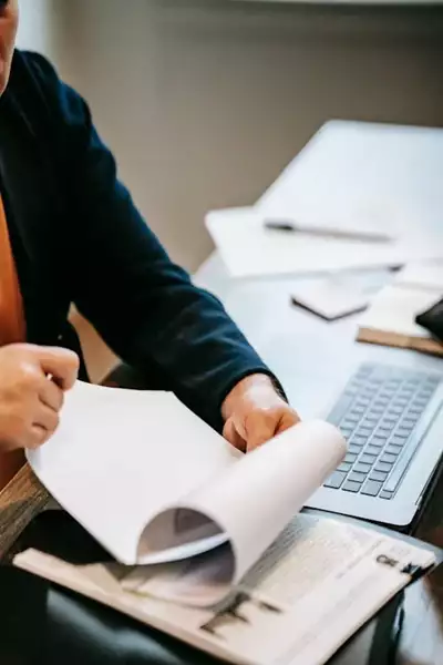 Person reviewing additional documents for an AFSL application at a desk with a laptop.