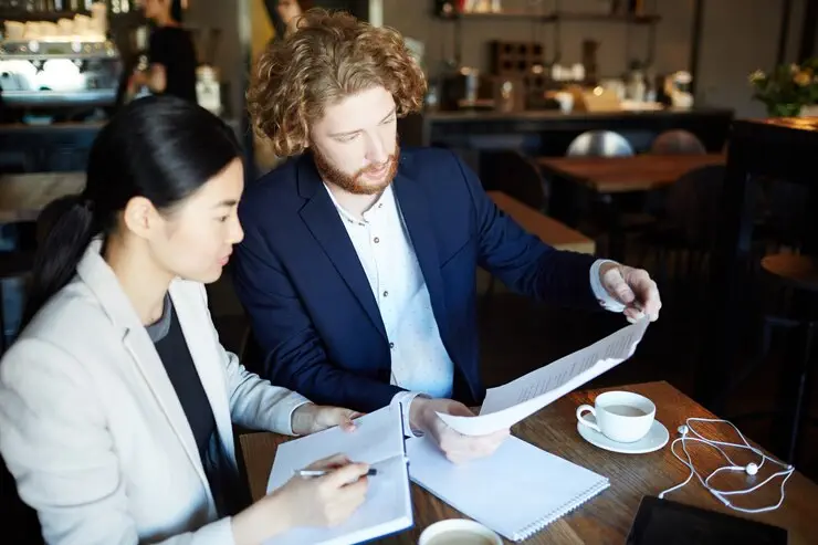 Two business professionals review documents for an AFSL licence application, ensuring Australian financial services compliance.