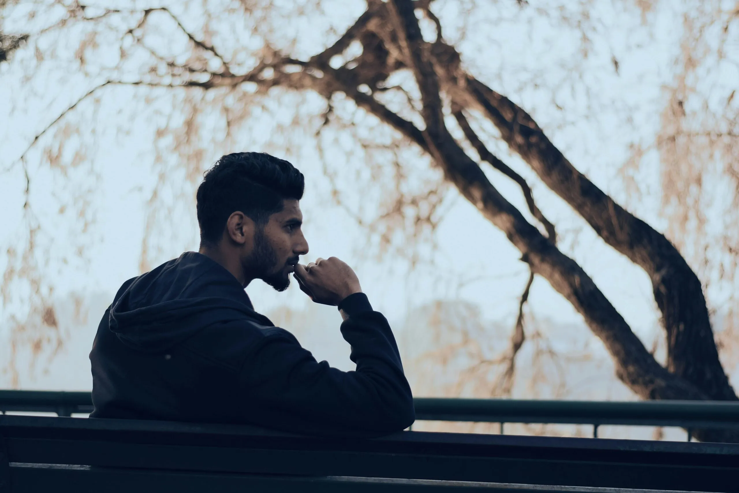 Man in contemplation, sitting on a park bench.