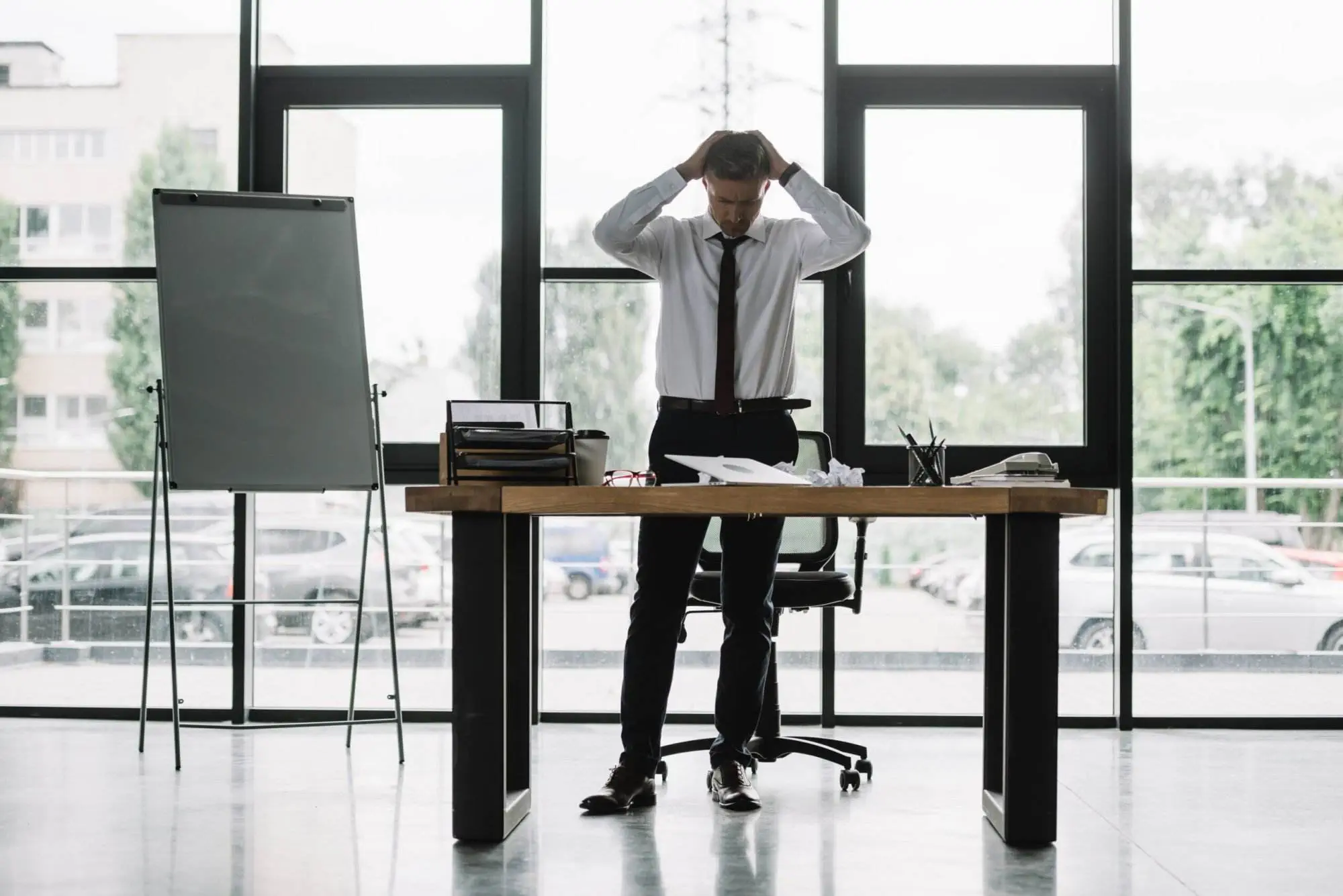 Stressed businessman at desk, overwhelmed by paperwork. Consequences of operating without an AFSL.