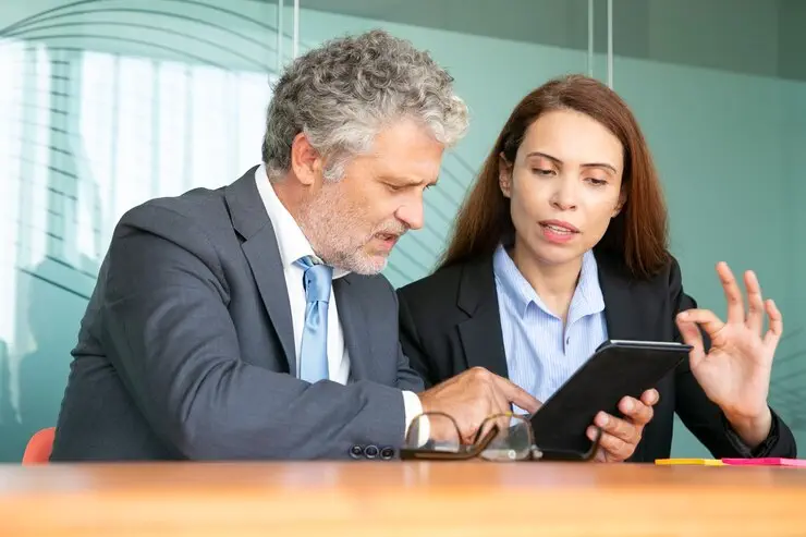 Two businesspeople review a tablet, discussing Australian credit licensee compliance training.