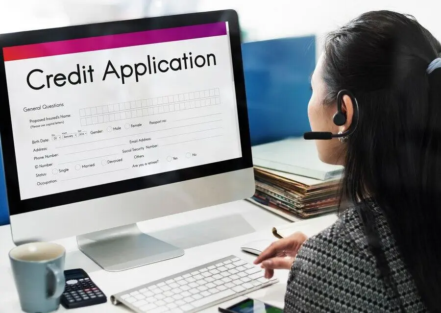 Woman completing online credit application form on computer. 