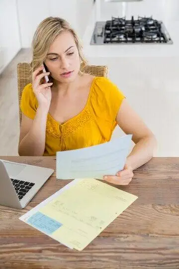 Woman reviewing documents while on a phone call, possibly related to an Australian credit licence application.