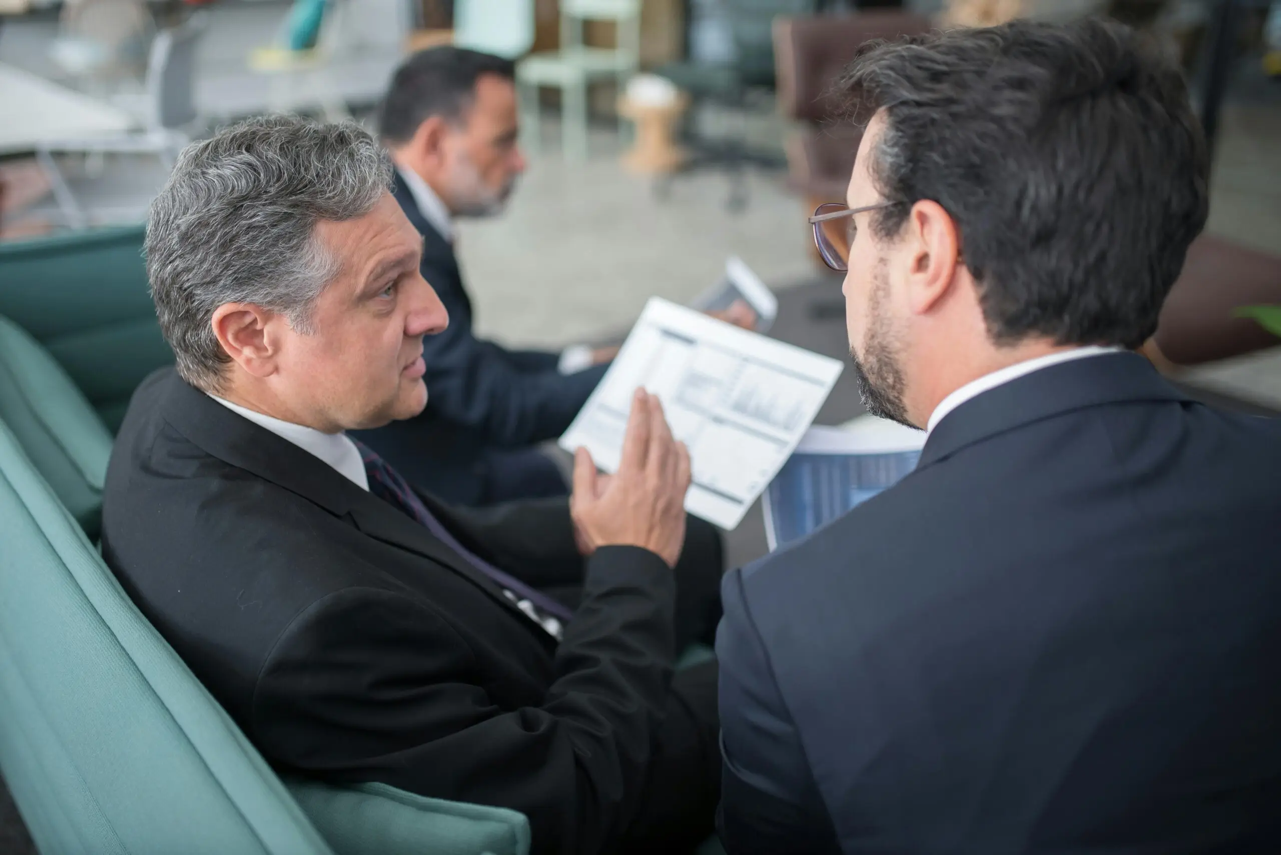 Three businessmen reviewing financial documents, discussing AFSL compliance.