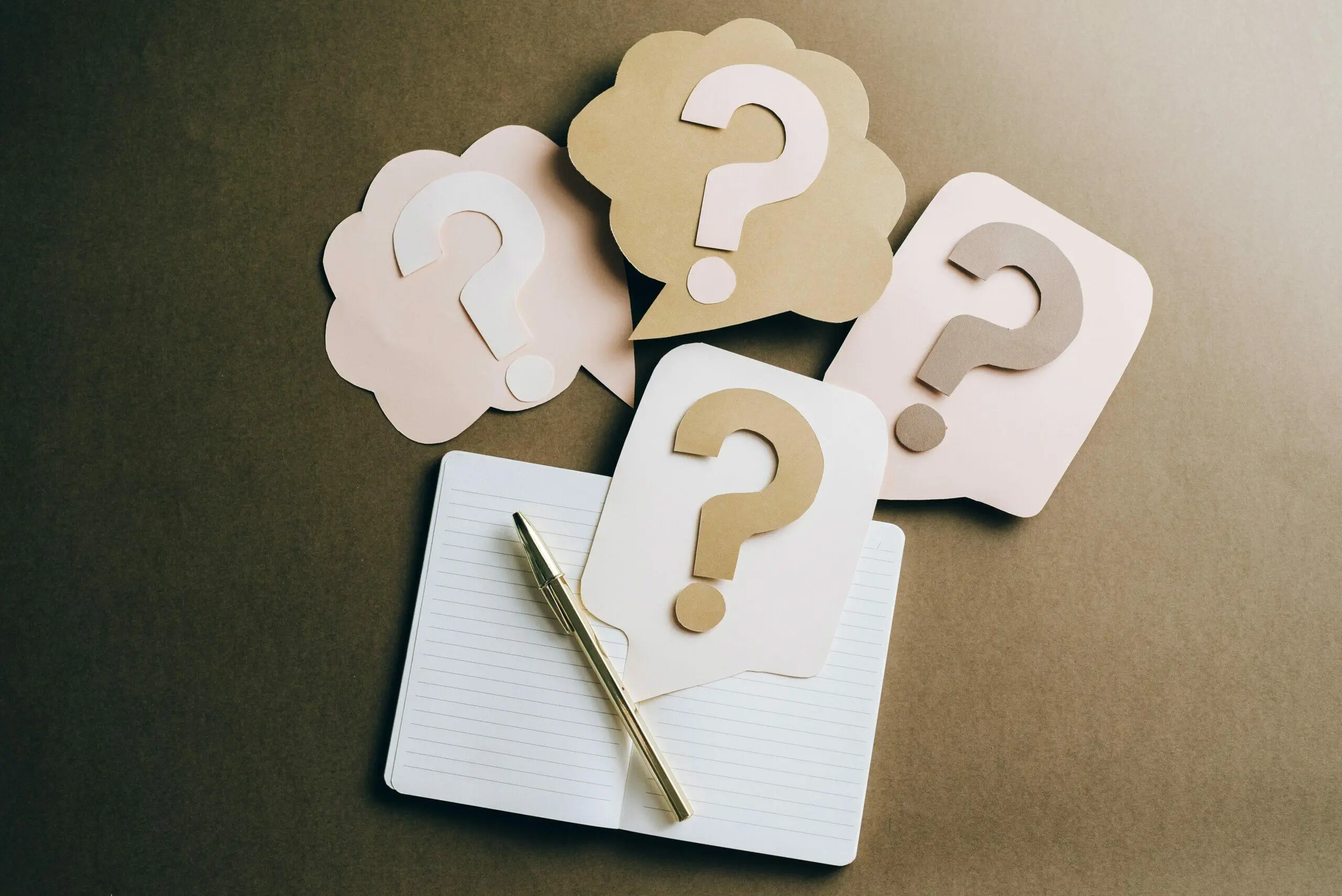 Notebook with pen and question mark speech bubbles; immigration lawyer consultation.