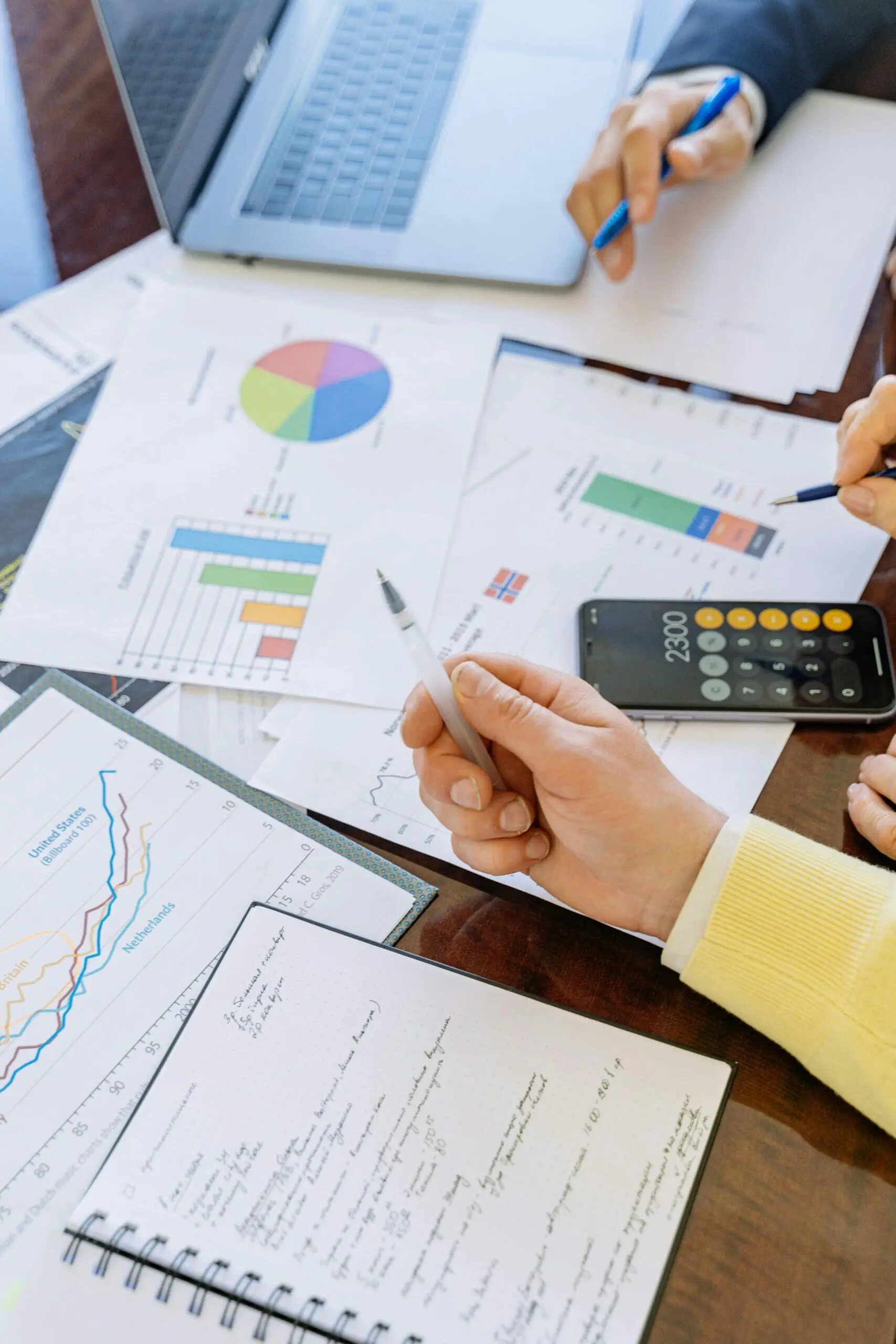 Close-up of hands reviewing financial documents, charts, and calculator; relevant to Australian credit license obligations.